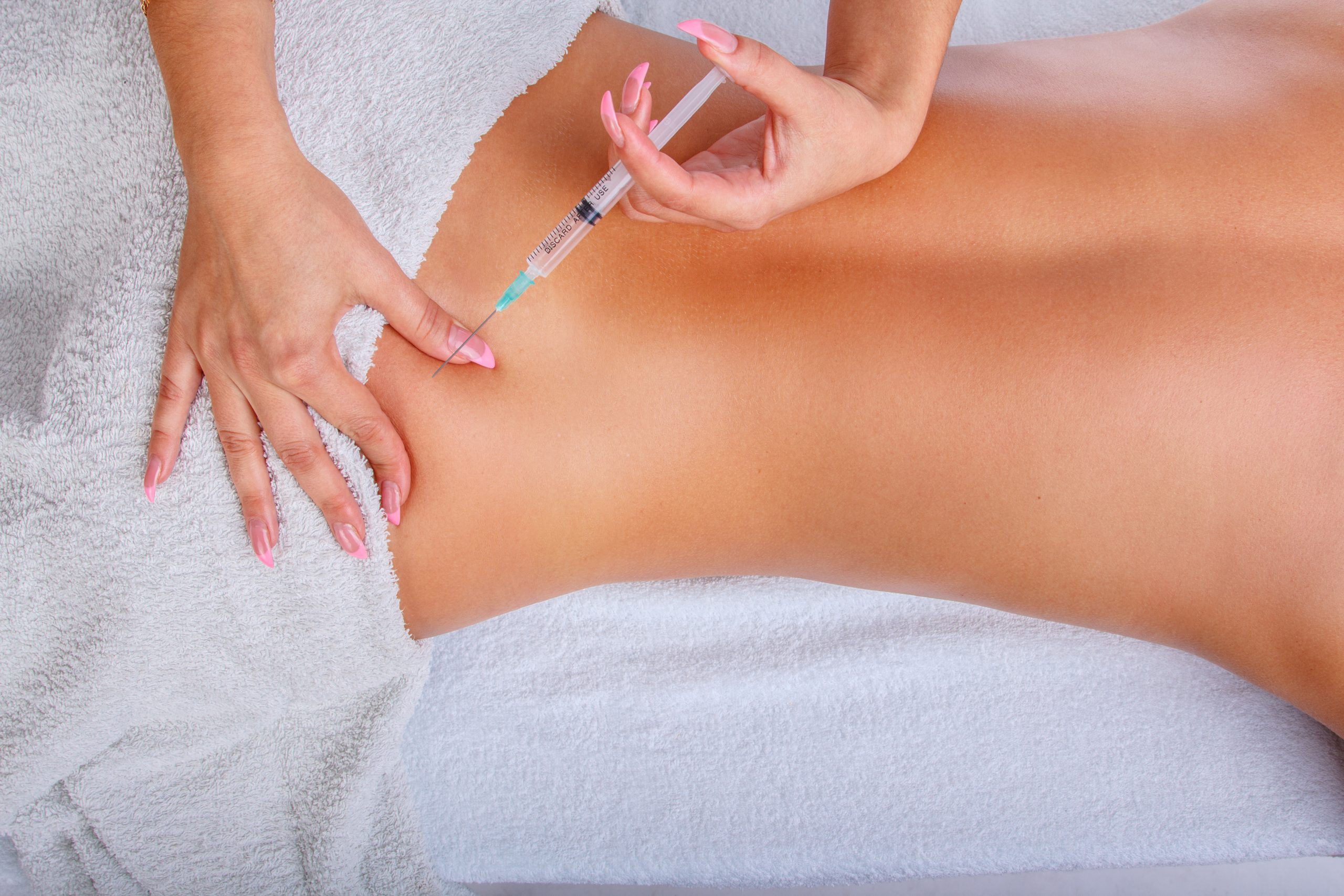 Syringe injection in to woman's back. Female enjoing relaxing back massage in cosmetology spa centre.