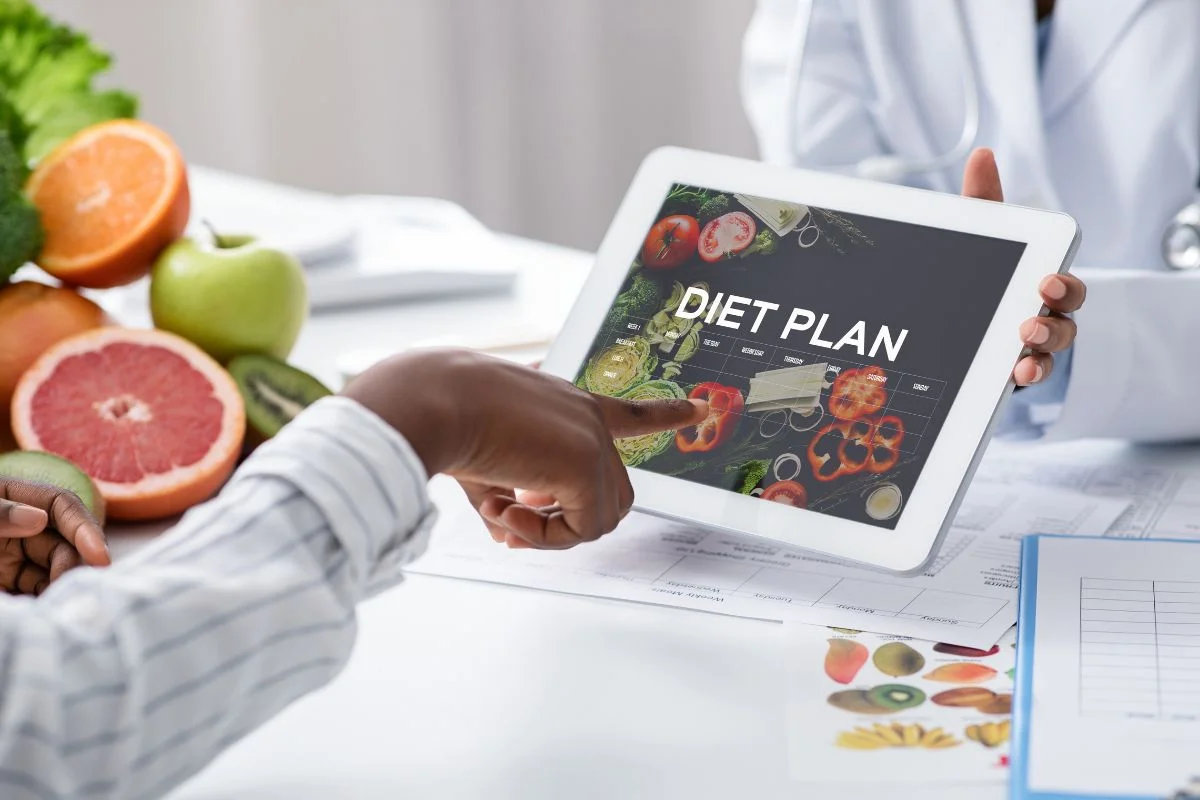 Profesionales ayudando a elegir un plan dietético a su cliente a través de una tablet.